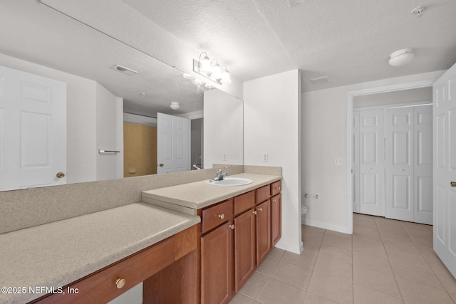 bathroom with a textured ceiling, toilet, vanity, visible vents, and tile patterned floors