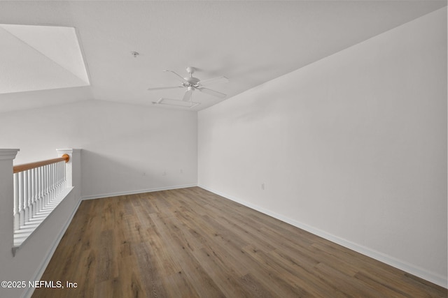 spare room with a ceiling fan, vaulted ceiling, baseboards, and wood finished floors