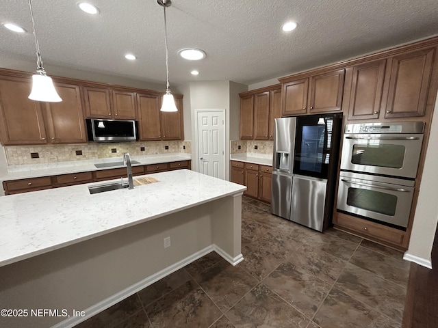 kitchen featuring pendant lighting, a sink, tasteful backsplash, stainless steel appliances, and light stone countertops