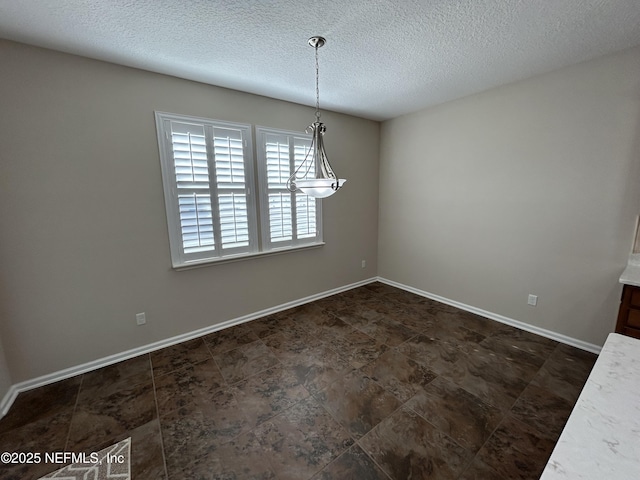 unfurnished dining area with baseboards and a textured ceiling