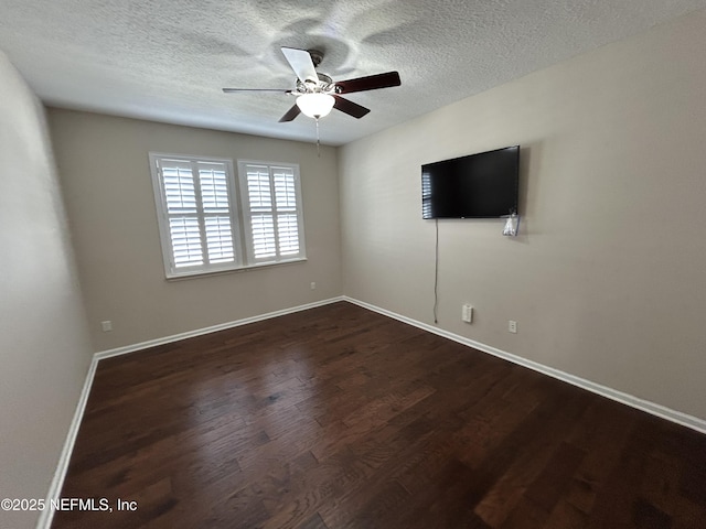 spare room with dark wood finished floors, a textured ceiling, baseboards, and ceiling fan