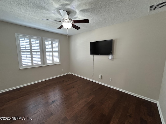 unfurnished room featuring visible vents, dark wood-type flooring, a ceiling fan, and a textured ceiling