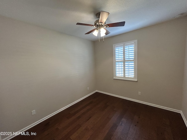 spare room featuring dark wood finished floors, ceiling fan, and baseboards