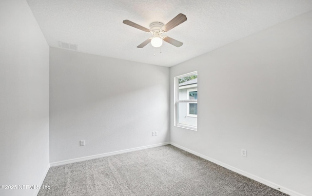 carpeted spare room with a ceiling fan, visible vents, a textured ceiling, and baseboards