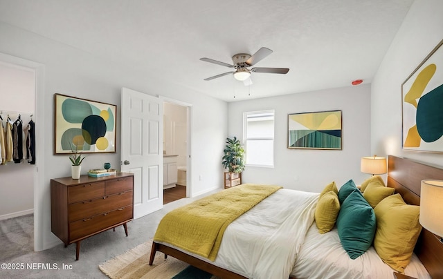 carpeted bedroom with ceiling fan, ensuite bath, and baseboards