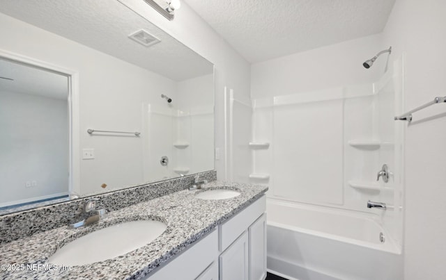 bathroom featuring a textured ceiling, shower / bathing tub combination, a sink, and visible vents