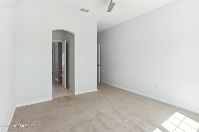 unfurnished bedroom featuring ceiling fan, arched walkways, light carpet, visible vents, and baseboards