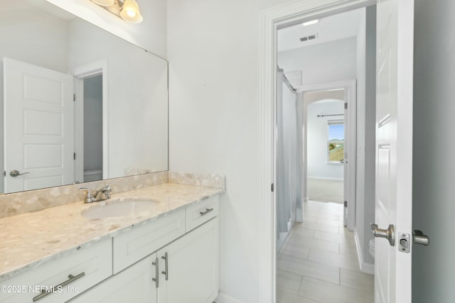 bathroom with visible vents, vanity, baseboards, and tile patterned floors