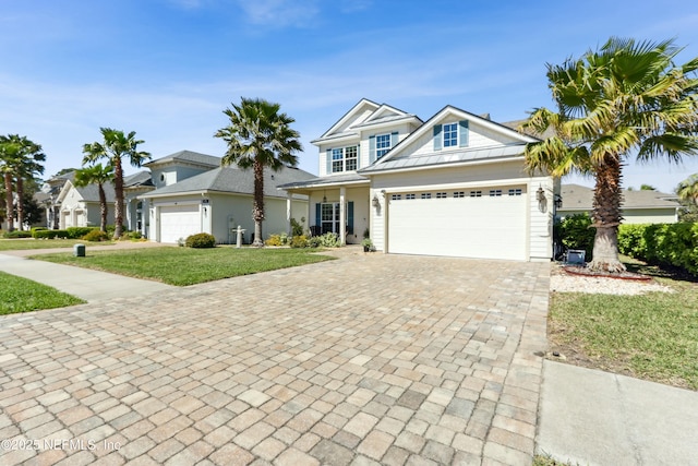 view of front facade featuring decorative driveway, an attached garage, a front yard, a standing seam roof, and metal roof