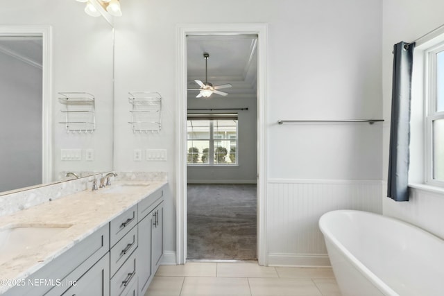 bathroom featuring double vanity, wainscoting, a soaking tub, tile patterned flooring, and a sink