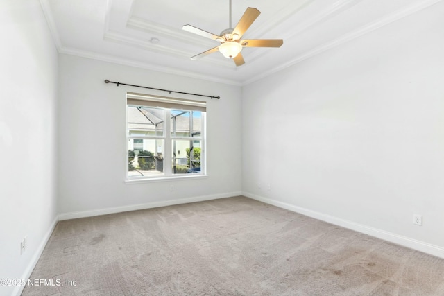 carpeted empty room with baseboards, a raised ceiling, a ceiling fan, and crown molding