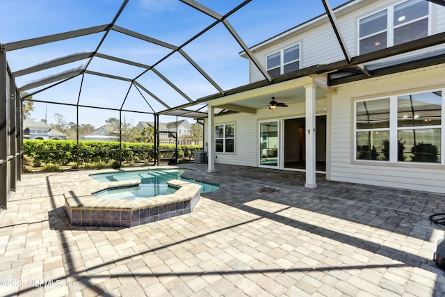 view of pool featuring a patio area, a pool with connected hot tub, glass enclosure, and ceiling fan