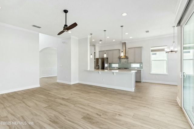 interior space featuring stainless steel fridge, visible vents, wall chimney exhaust hood, open floor plan, and gray cabinetry