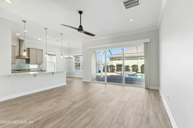 unfurnished living room with visible vents, baseboards, ceiling fan, ornamental molding, and light wood-type flooring