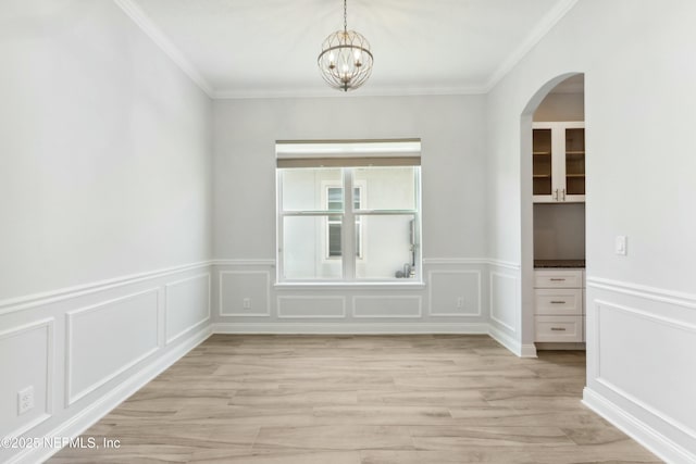 unfurnished dining area with a notable chandelier, a decorative wall, light wood-style flooring, and crown molding