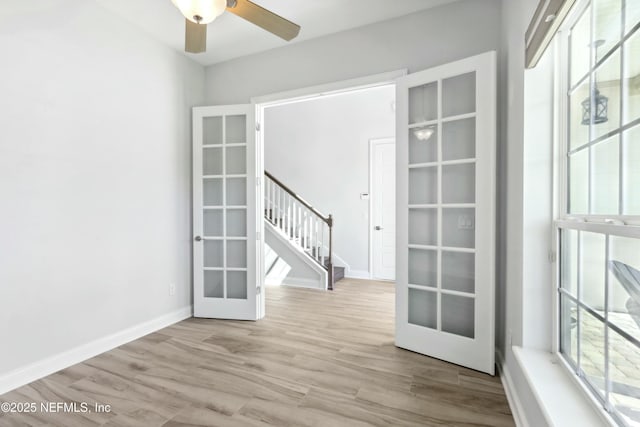 spare room with ceiling fan, wood finished floors, baseboards, stairs, and french doors