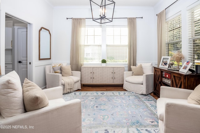 living area with a notable chandelier, wood finished floors, and crown molding