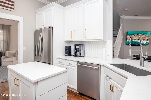 kitchen with wood finished floors, a sink, appliances with stainless steel finishes, backsplash, and crown molding