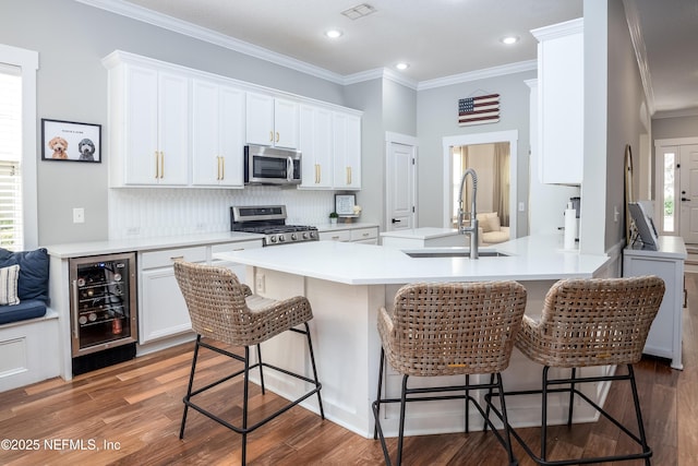 kitchen with stainless steel appliances, wine cooler, a sink, and white cabinets