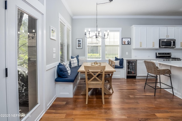 dining space featuring beverage cooler, dark wood finished floors, breakfast area, ornamental molding, and an inviting chandelier