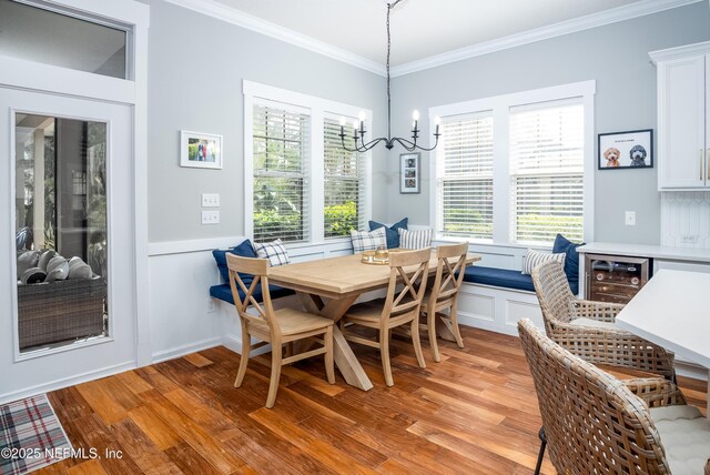 dining room with beverage cooler, plenty of natural light, light wood-type flooring, and crown molding