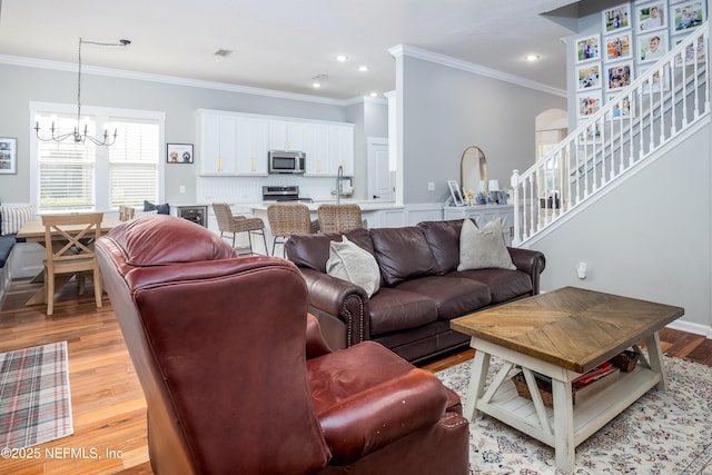 living room featuring light wood-style floors, stairs, and ornamental molding