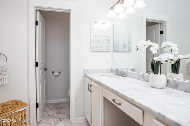 bathroom featuring toilet, marble finish floor, baseboards, and vanity