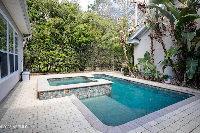 view of swimming pool featuring a patio area, a pool with connected hot tub, and fence