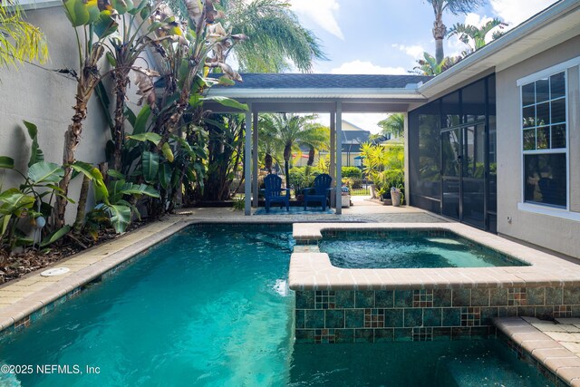 pool with a patio, a lanai, and an in ground hot tub