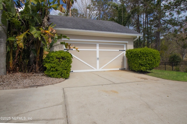 garage featuring driveway and fence