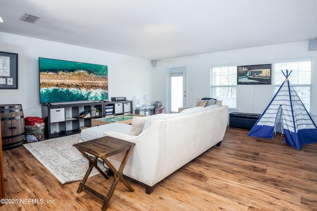 living area featuring visible vents and wood finished floors