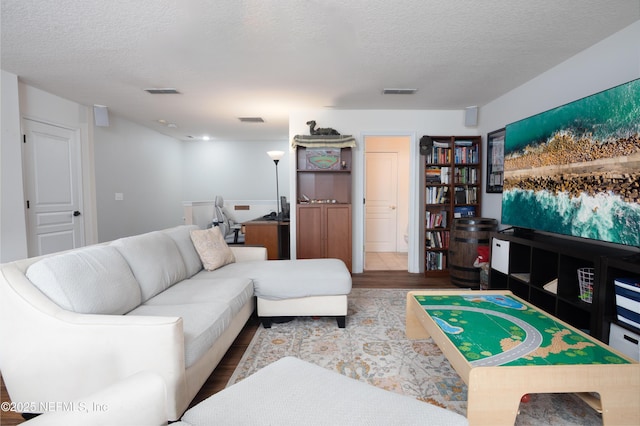 living area with a textured ceiling, visible vents, and wood finished floors