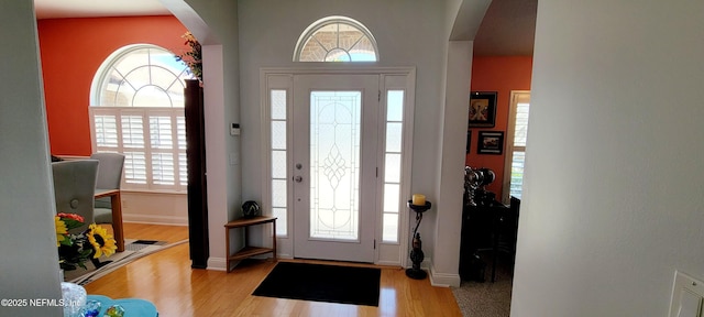 foyer entrance featuring arched walkways, plenty of natural light, and wood finished floors