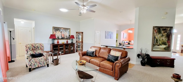 carpeted living area featuring ceiling fan, arched walkways, recessed lighting, a sink, and ornamental molding