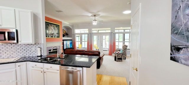 kitchen with tasteful backsplash, stainless steel microwave, open floor plan, ornamental molding, and a sink