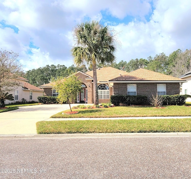 view of front of home with driveway, a front yard, and brick siding