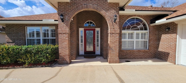 property entrance featuring brick siding and roof with shingles