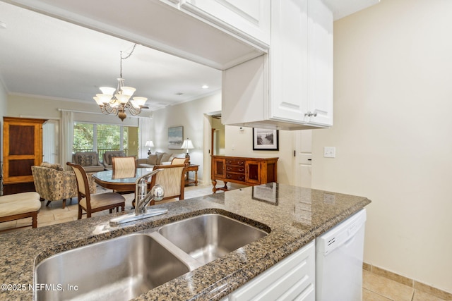 kitchen with white dishwasher, a sink, white cabinetry, dark stone counters, and an inviting chandelier