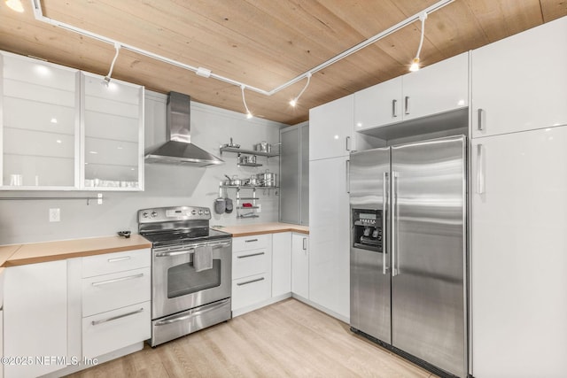 kitchen with stainless steel appliances, wall chimney range hood, open shelves, and light countertops