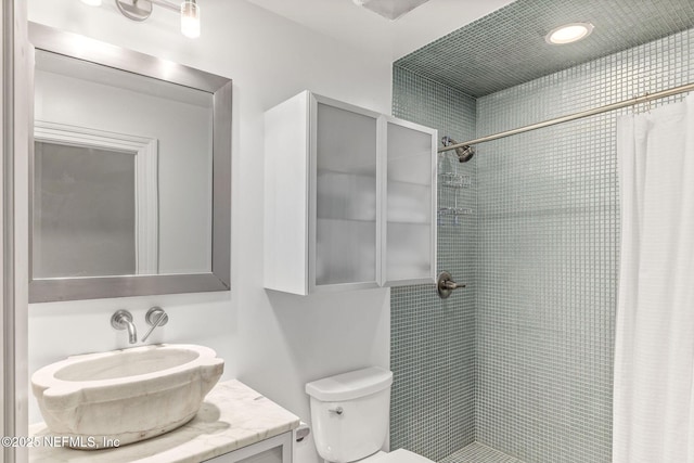 full bathroom with toilet, a tile shower, and vanity