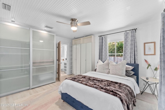 bedroom featuring connected bathroom, wood finished floors, visible vents, and a ceiling fan