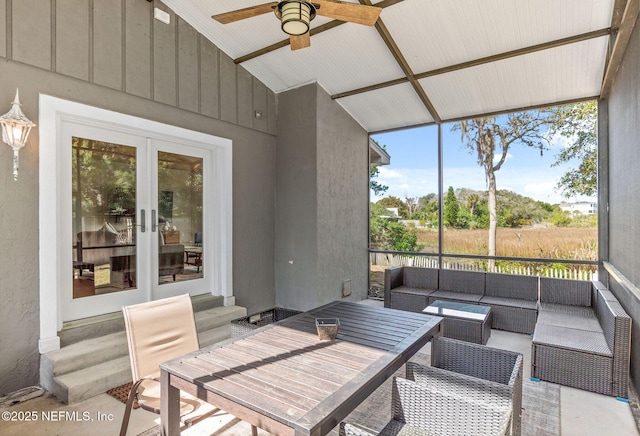 sunroom with vaulted ceiling, a ceiling fan, and french doors