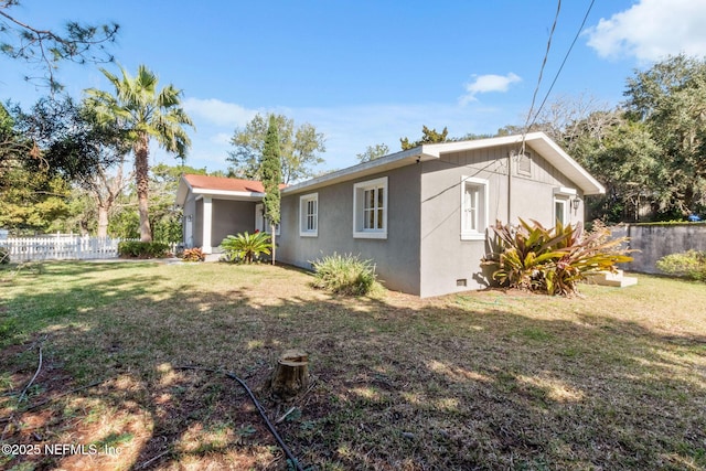 exterior space featuring crawl space, stucco siding, fence, and a yard