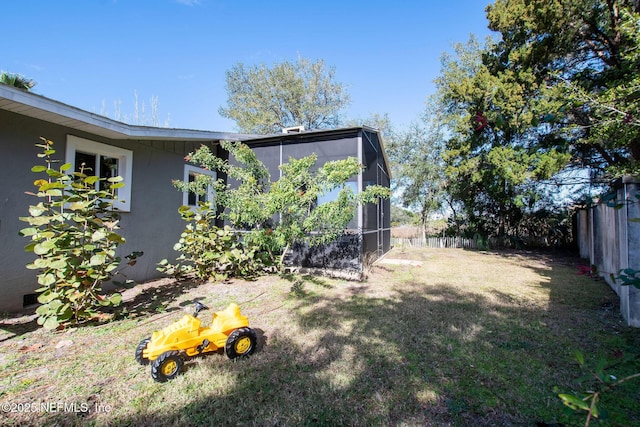 view of yard featuring glass enclosure and fence