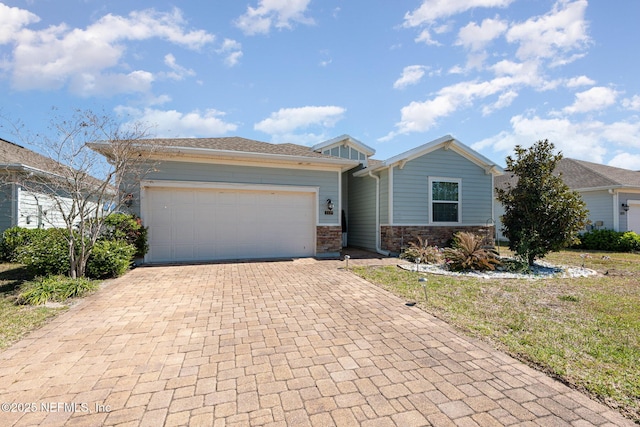 view of front facade with a garage, decorative driveway, and stone siding