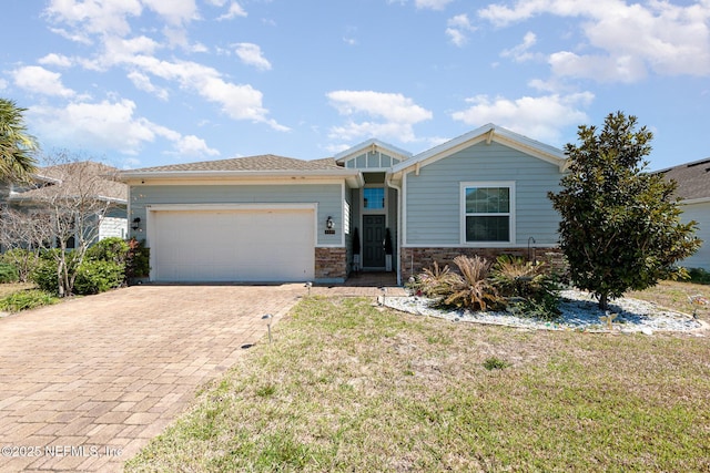 view of front of house featuring stone siding, a front lawn, decorative driveway, and an attached garage