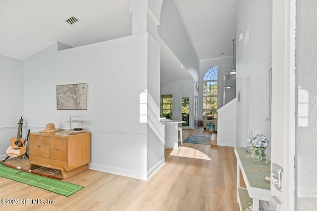 foyer with a ceiling fan, wood finished floors, visible vents, and baseboards