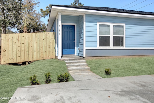 entrance to property featuring a yard and fence