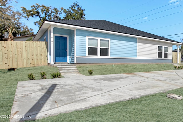 view of front of property with a shingled roof, a front yard, and fence