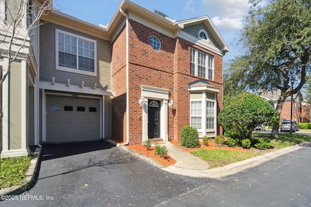 view of front of house with an attached garage, driveway, and brick siding